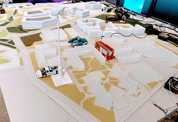 Mock-up of streets with police car, red bus & cables