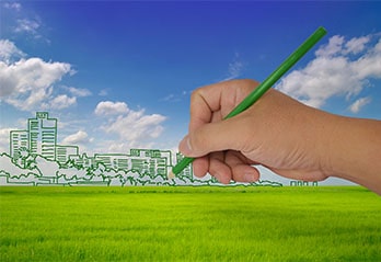 Hand drawing a green smart city with green pencil on grass