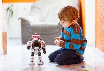 Little boy playing with remote control robot on the floor