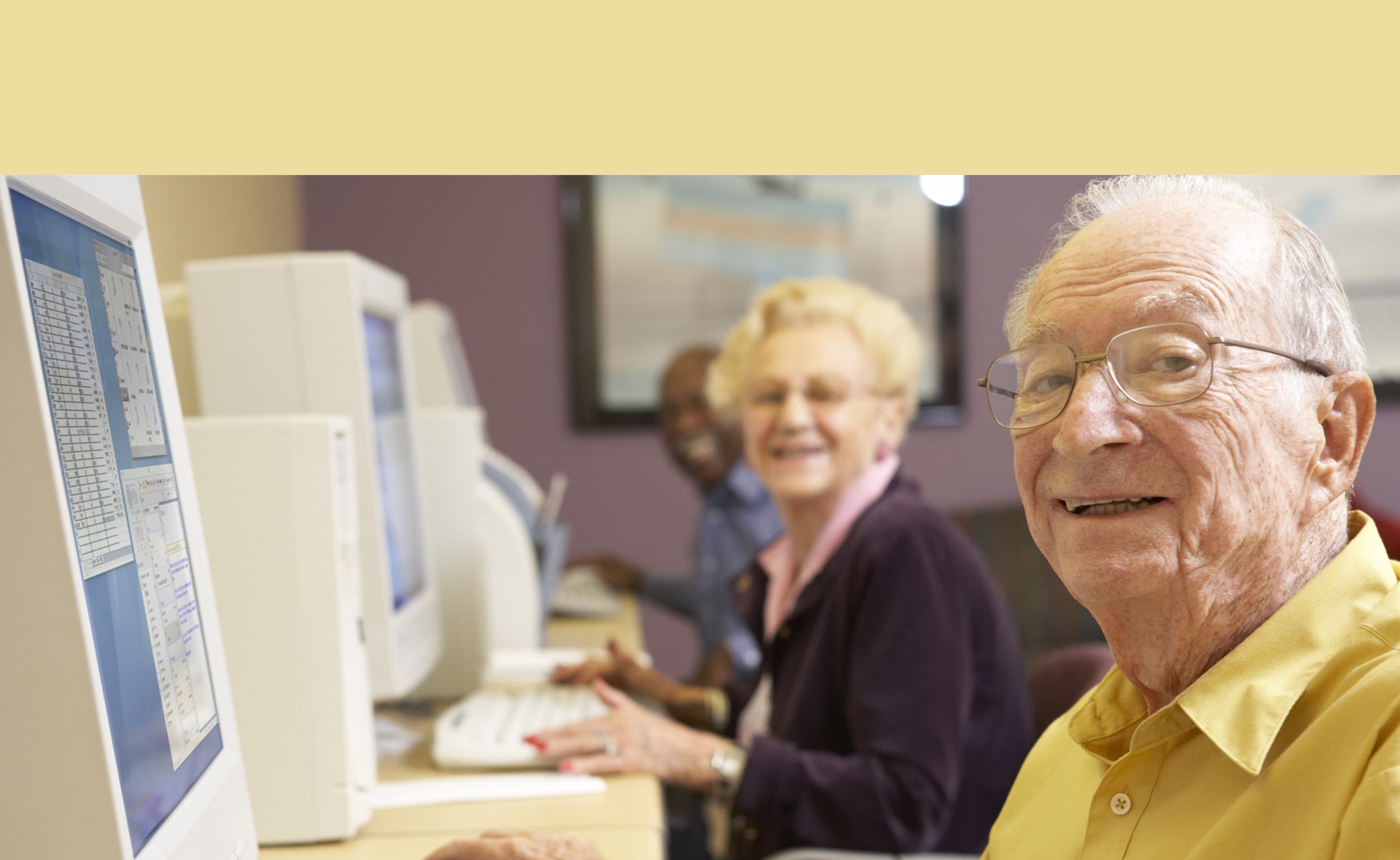 An elderly man and woman smiling in front of PCs