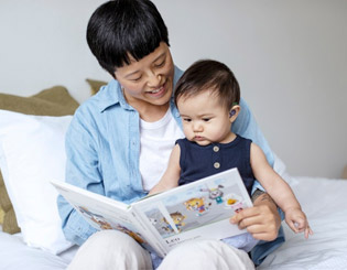 A woman reading to his granddaughter wearing a hearing aid