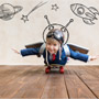 A child wearing an aviator hat rides a skateboard as if he were flying