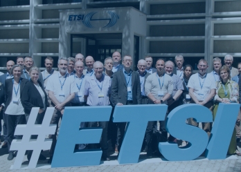 Group of professionals standing outdoors in front of large “#ETSI” letters outside the ETSI building.